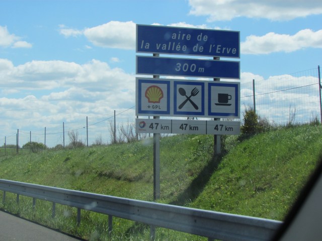 This is a typical rest stop sign.. When the sign starts with "aire de" it means it a rest stop. Then the smaller signs below it tell which services are available. In this case it was a Shell gas station with food and coffee. Very similar to a lot of our freeway signs.